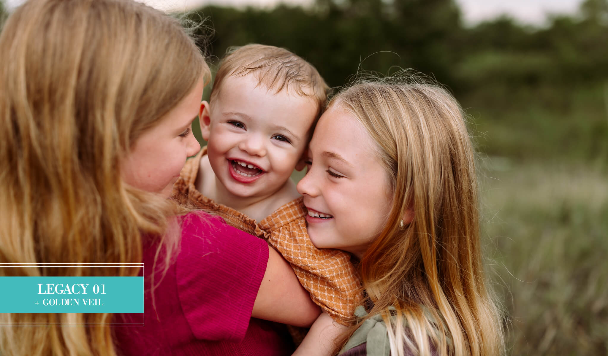 A close-up lifestyle photograph of three children outdoors, with two girls hugging a smiling toddler, edited with Legacy Lightroom Presets from Pretty Presets