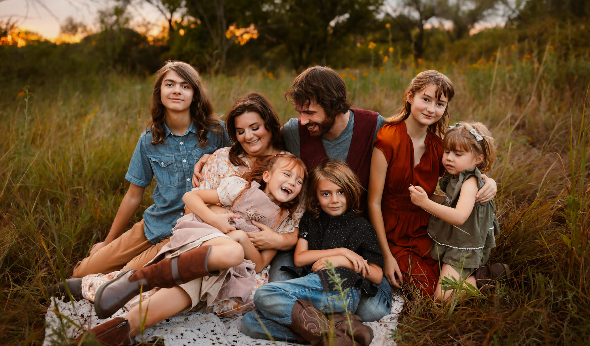 A family of six posing together outdoors in a grassy field at sunset edited with Legacy Lightroom Presets from Pretty Presets